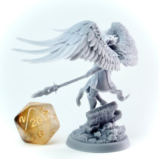 Gray angel figurine with wings and spear next to a gold polyhedral dice on a white background