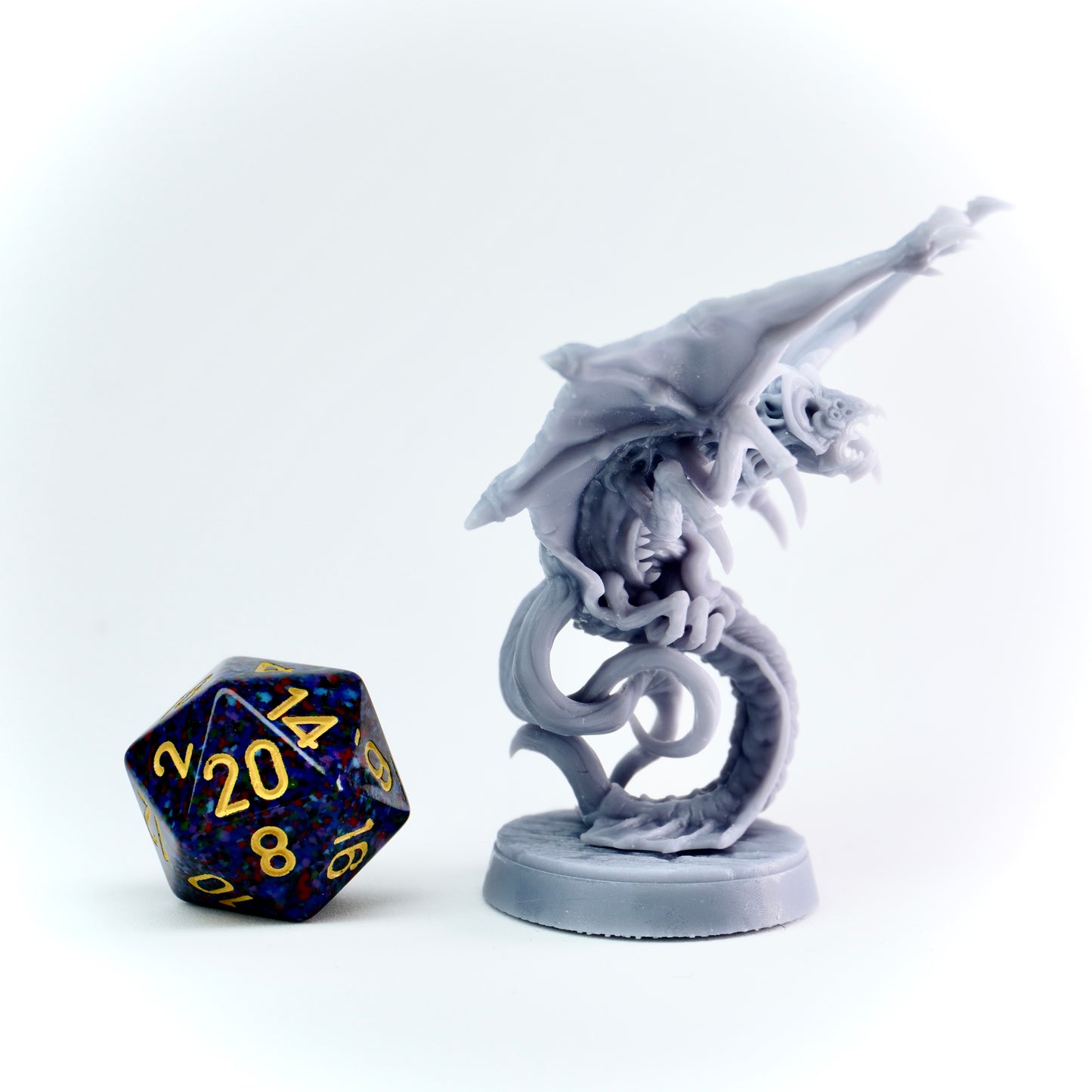 Gray fantasy figurine with a cloaker monster and a polyhedral dice on a white background