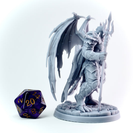 Gray fantasy demon figurine with wings and a spear next to a purple polyhedral dice on a white background