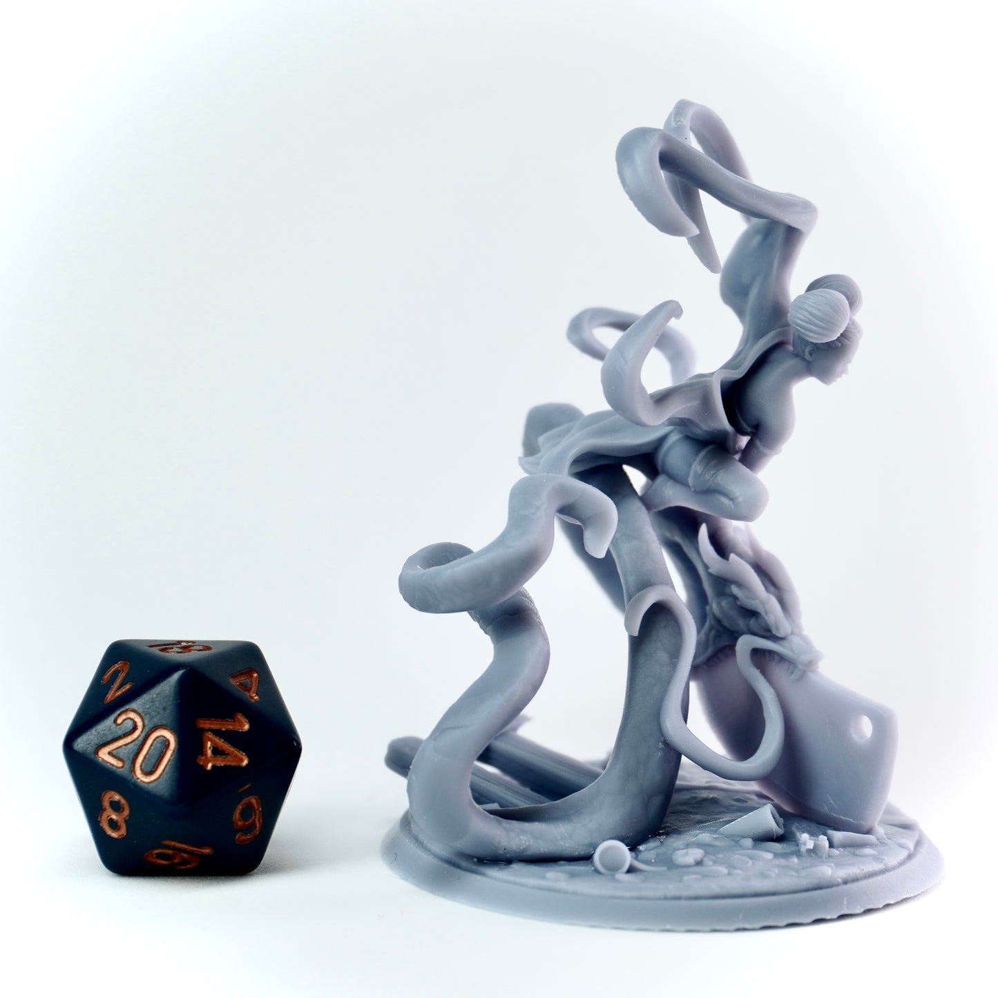 Gray fantasy figurine with dragon spirit next to a black polyhedral dice on a white backgrounds