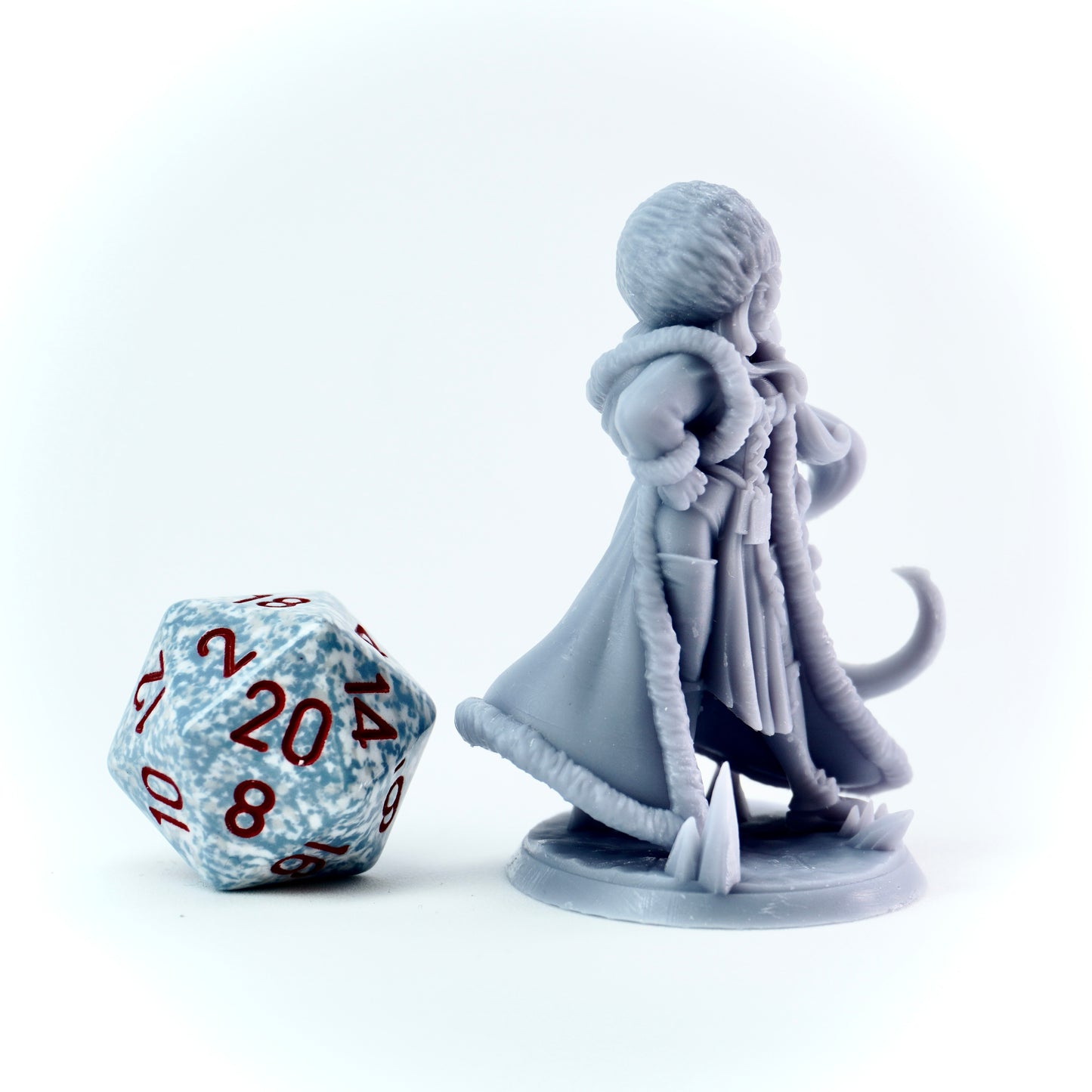 Gray miniature figure of a female character with a large die on a white background