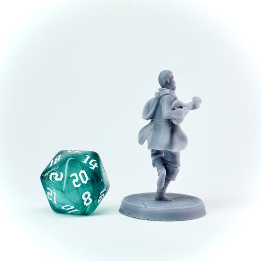 Gray miniature figurine of a character with a lute and a green polyhedral dice on a white background
