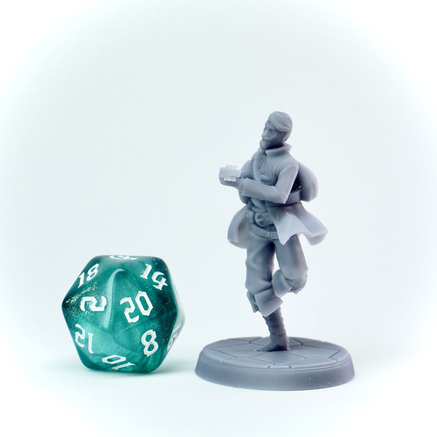 Gray miniature figure of a character holding a lute next to a green polyhedral dice on a white background