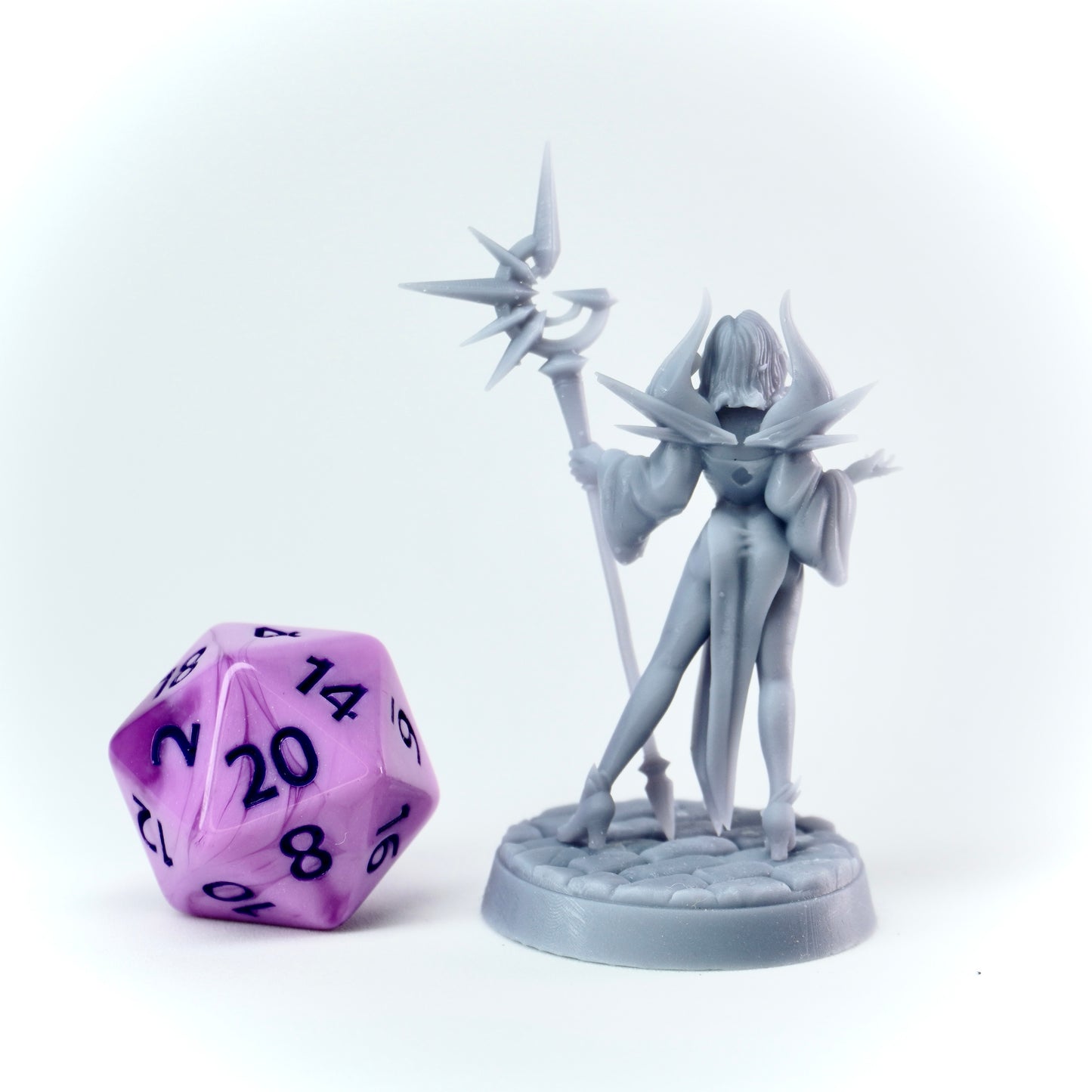 Gray fantasy figurine with a purple polyhedral dice on a white background