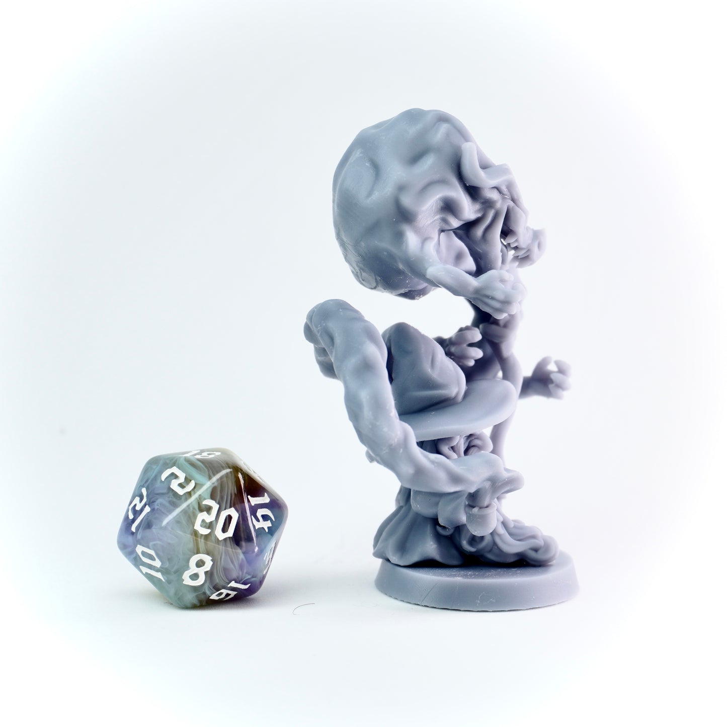 Gray fantasy figurine of a creature with a large smoke monster next to a polyhedral dice on a white background