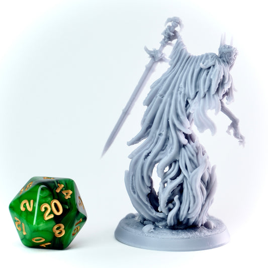 Gray fantasy ghost figure with long hood and a sword next to a green polyhedral dice on a white background