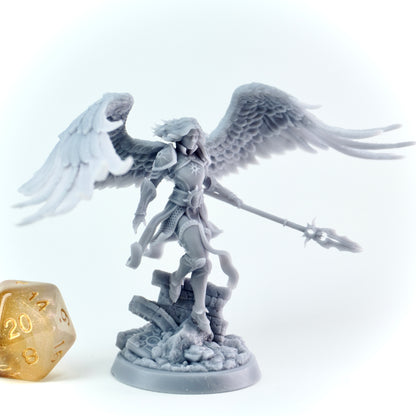 Gray angel figurine with wings and a spear next to a gold die on a white background