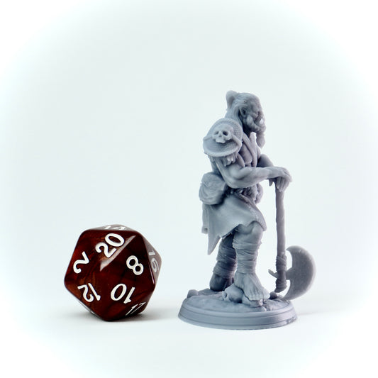 Gray miniature figure of a orc warrior with an axe next to a 20-sided die on a white background