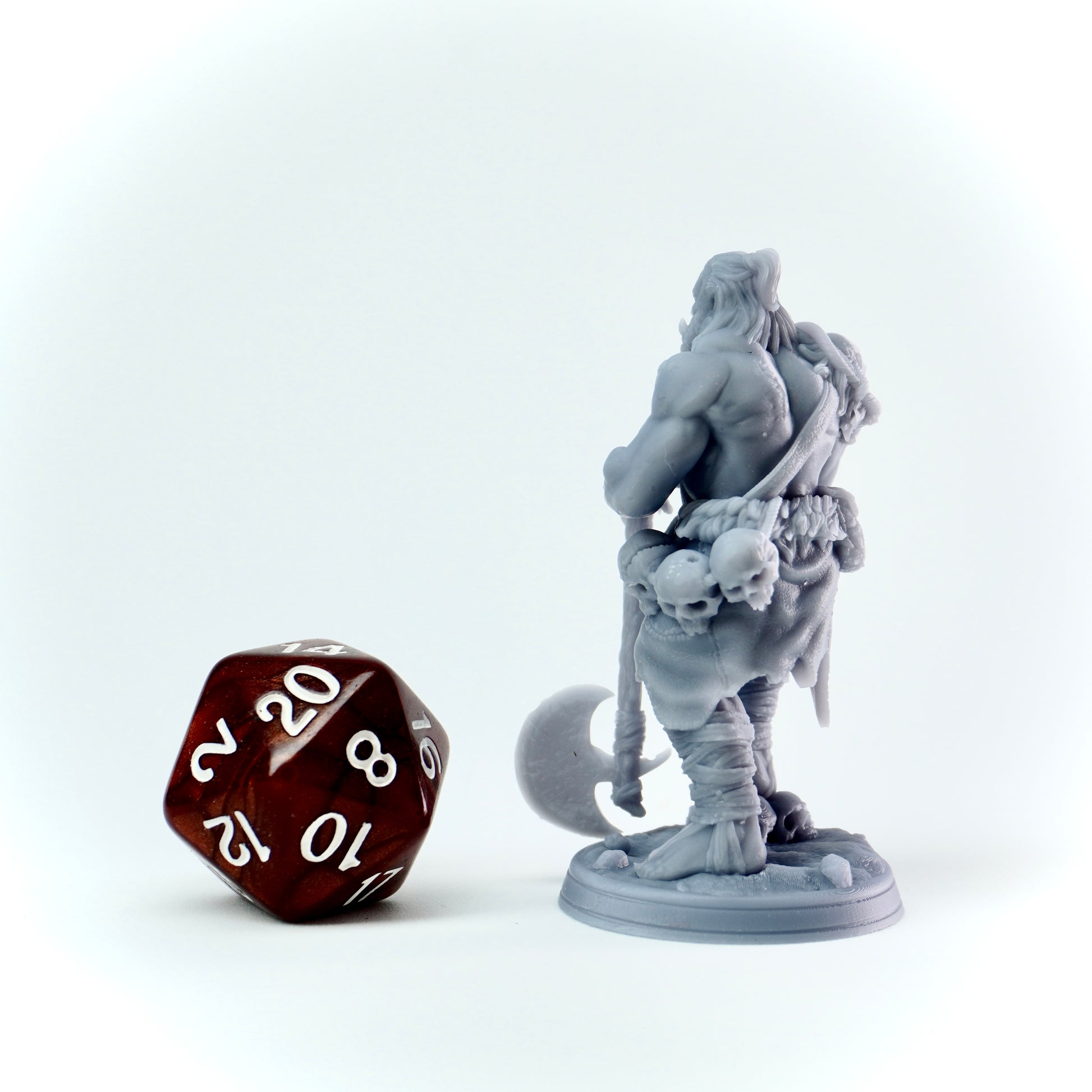 Gray fantasy figurine with a brown polyhedral dice on a white background