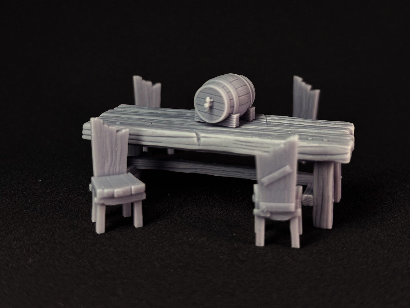 3D-printed miniature table with chairs and a barrel on a black background
