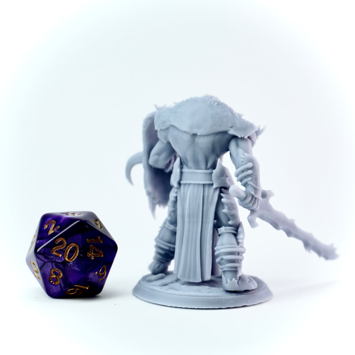 Gray fantasy figurine with a purple and gold die on a white background