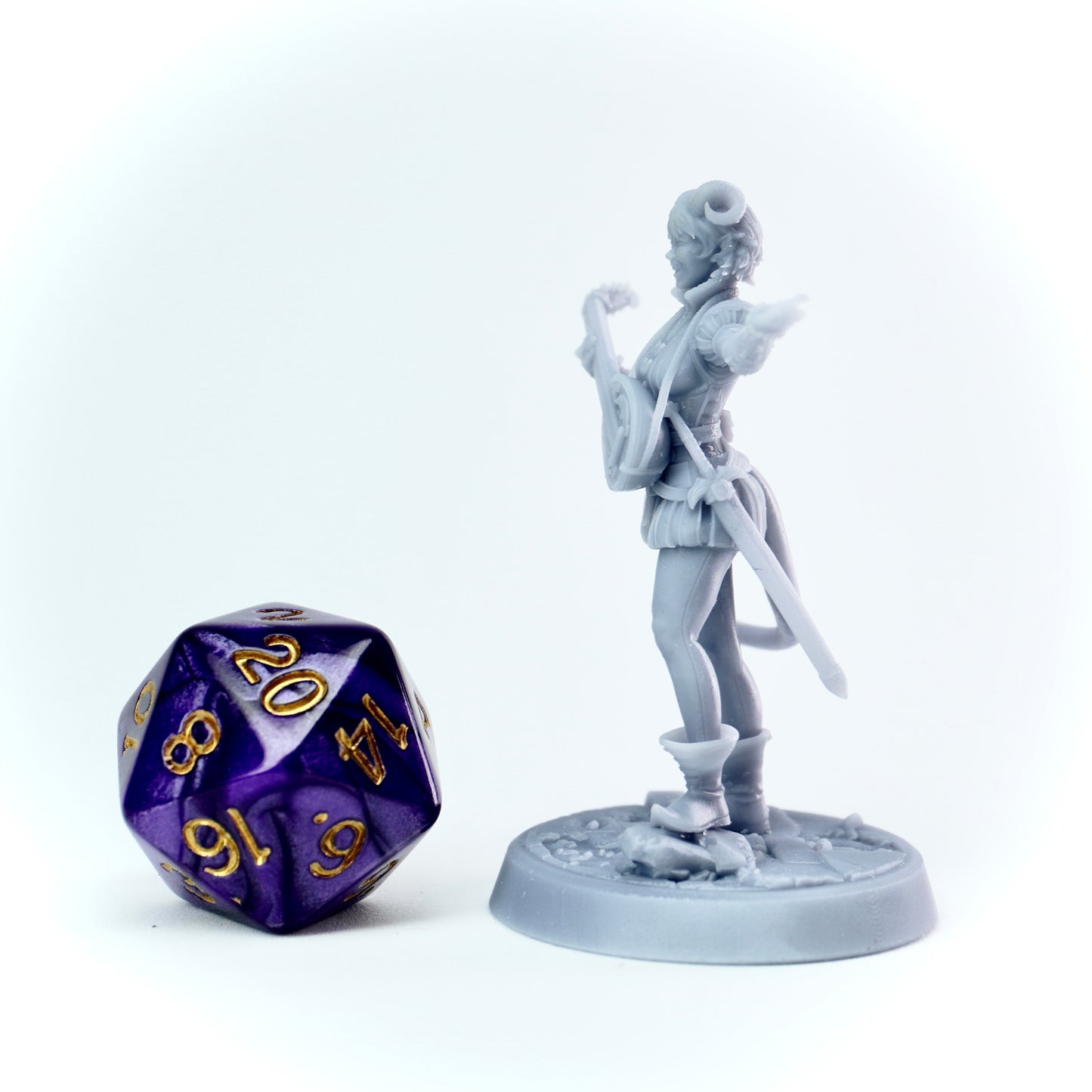 Gray miniature figurine of a female bard tiefling with a polyhedral dice on a white background