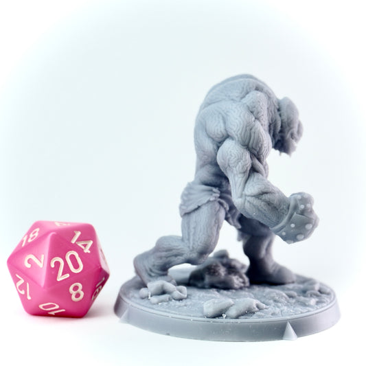 Gray fantasy figurine of a golem creature with a pink polyhedral dice on a white background