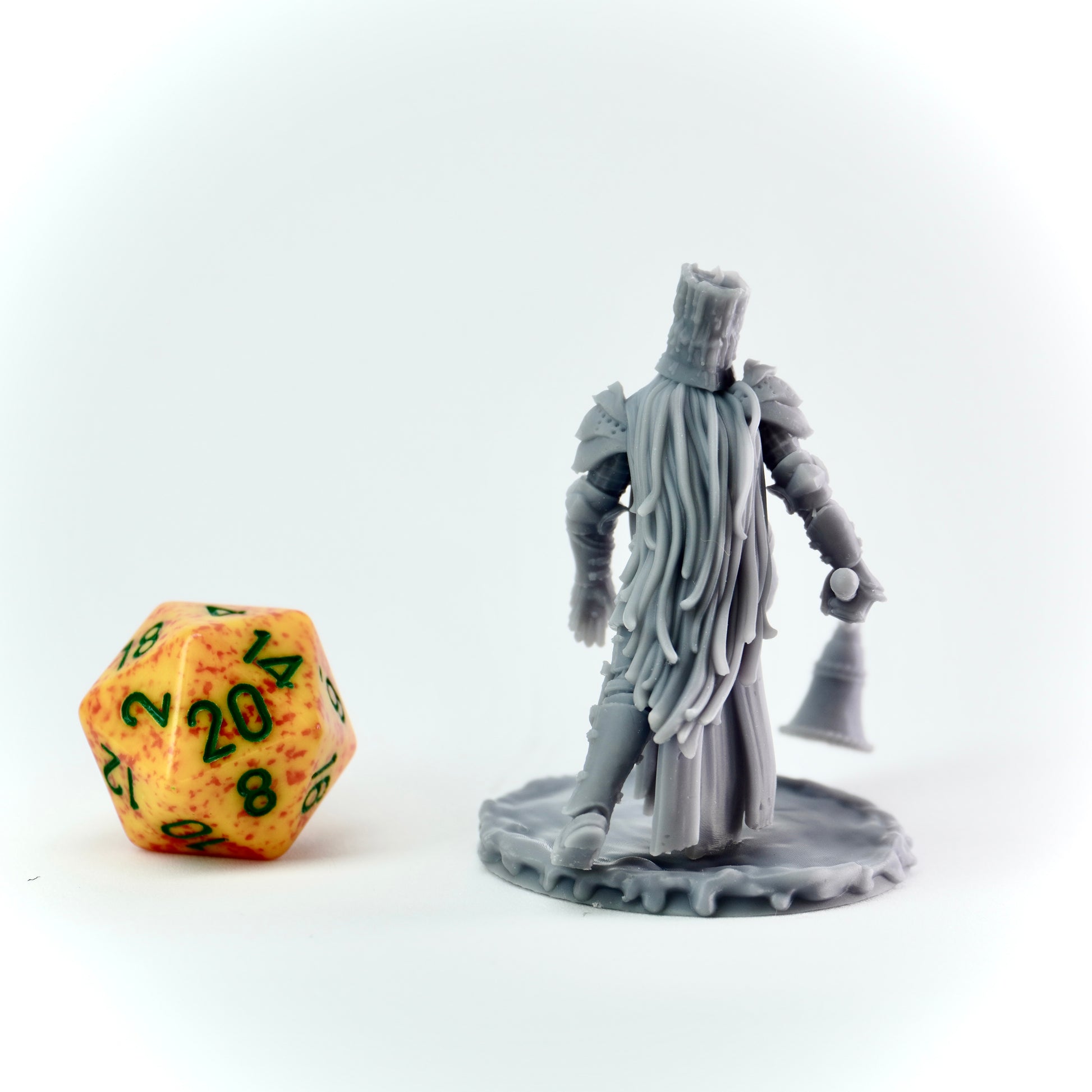 Gray miniature figure of a warrior with a large candle snuffer next to a d20 dice on a white background