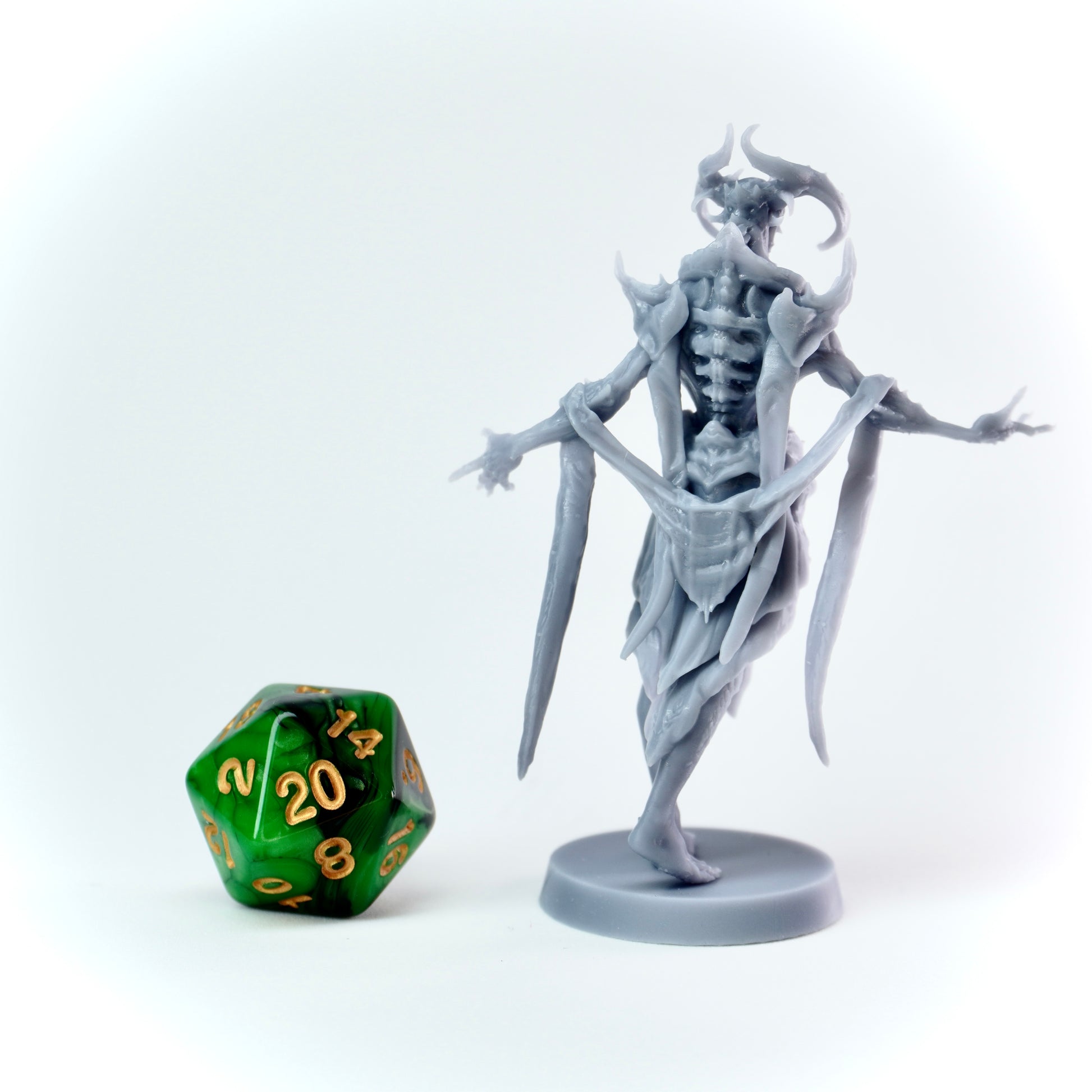 Gray fantasy figurine next to a green polyhedral dice on a white background