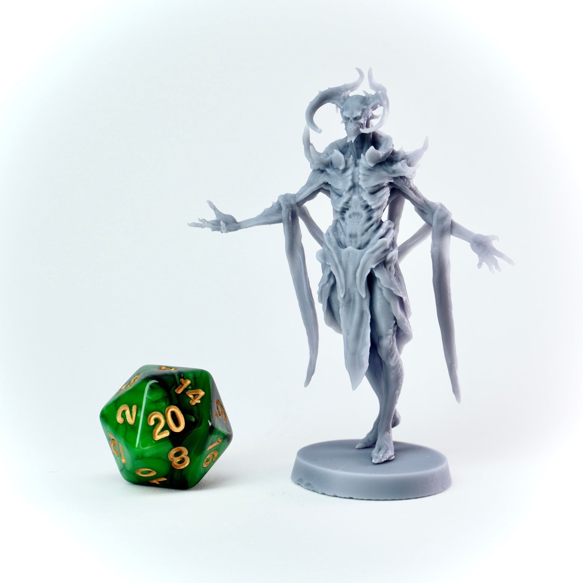 Gray fantasy figurine next to a green polyhedral dice on a white background