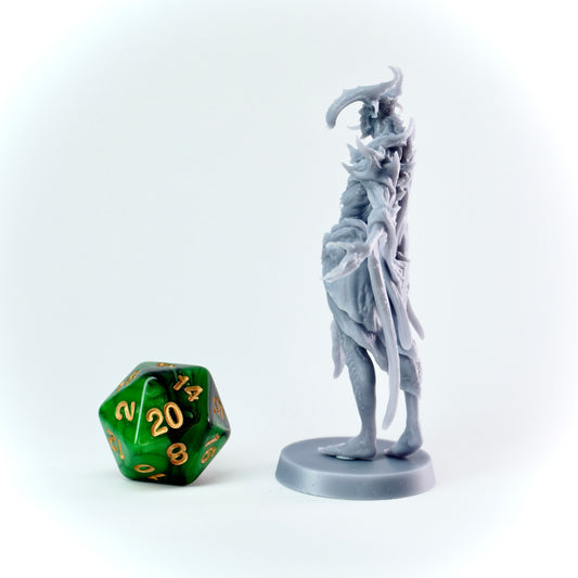 Gray fantasy figurine next to a green polyhedral dice on a white background