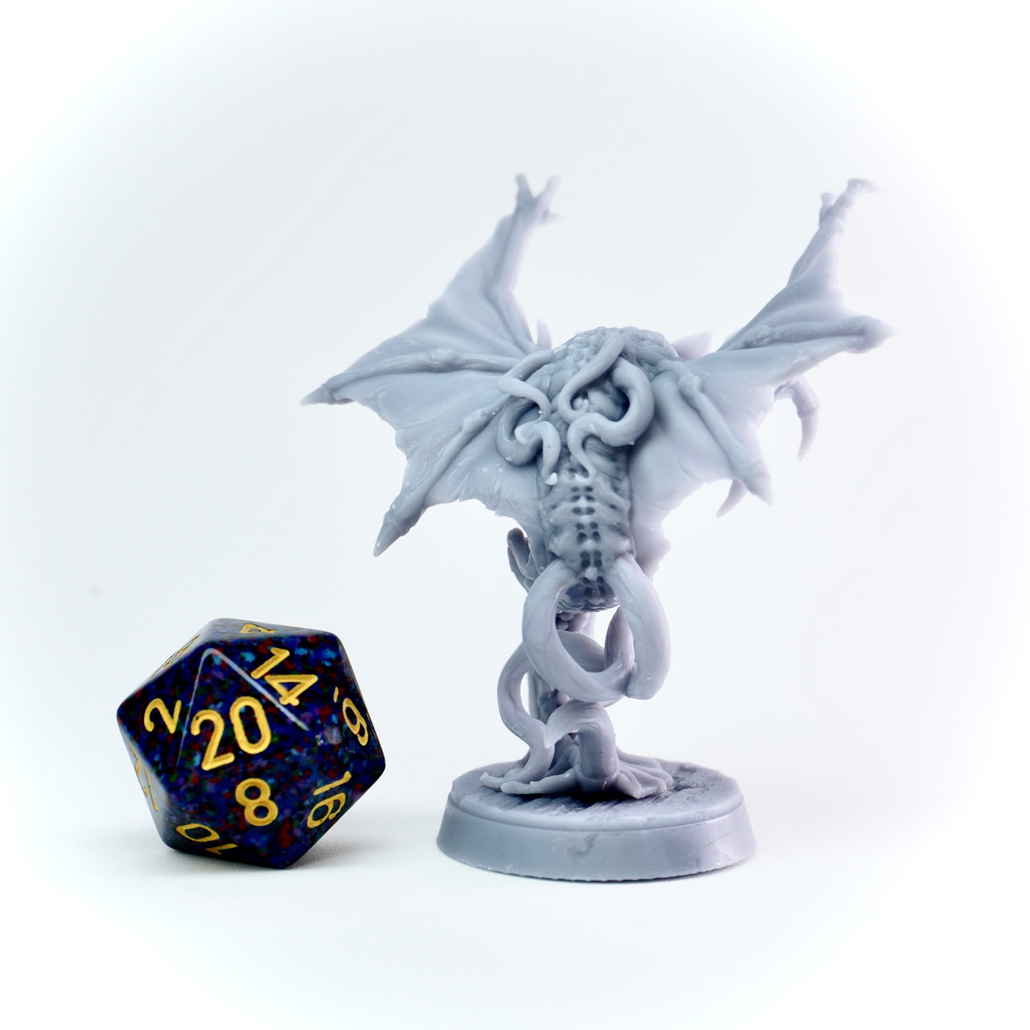 White cloaker monster figurine with a blue and yellow polyhedral dice on a white background