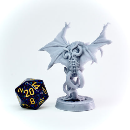 White cloaker monster figurine with a blue and yellow polyhedral dice on a white background