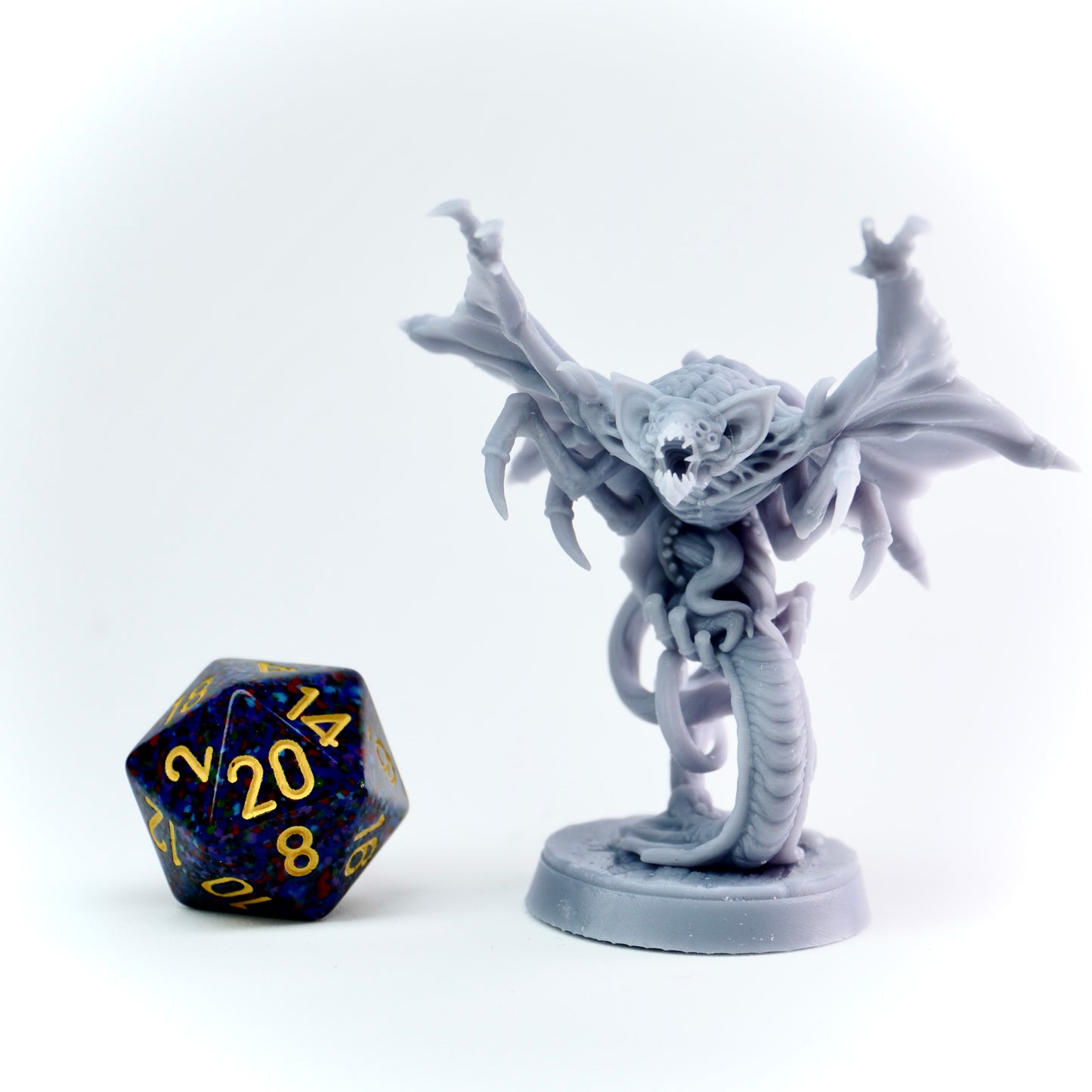 Gray cloaker monster figurine with a blue and gold polyhedral dice on a white background