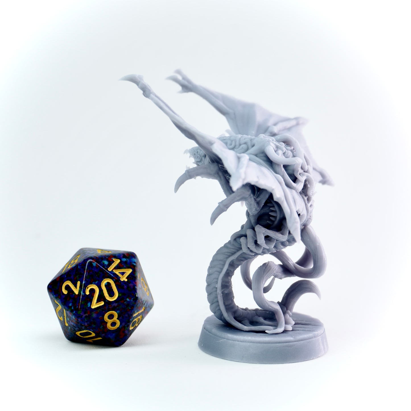Gray cloaker monster figurine with a blue and gold polyhedral dice on a white background