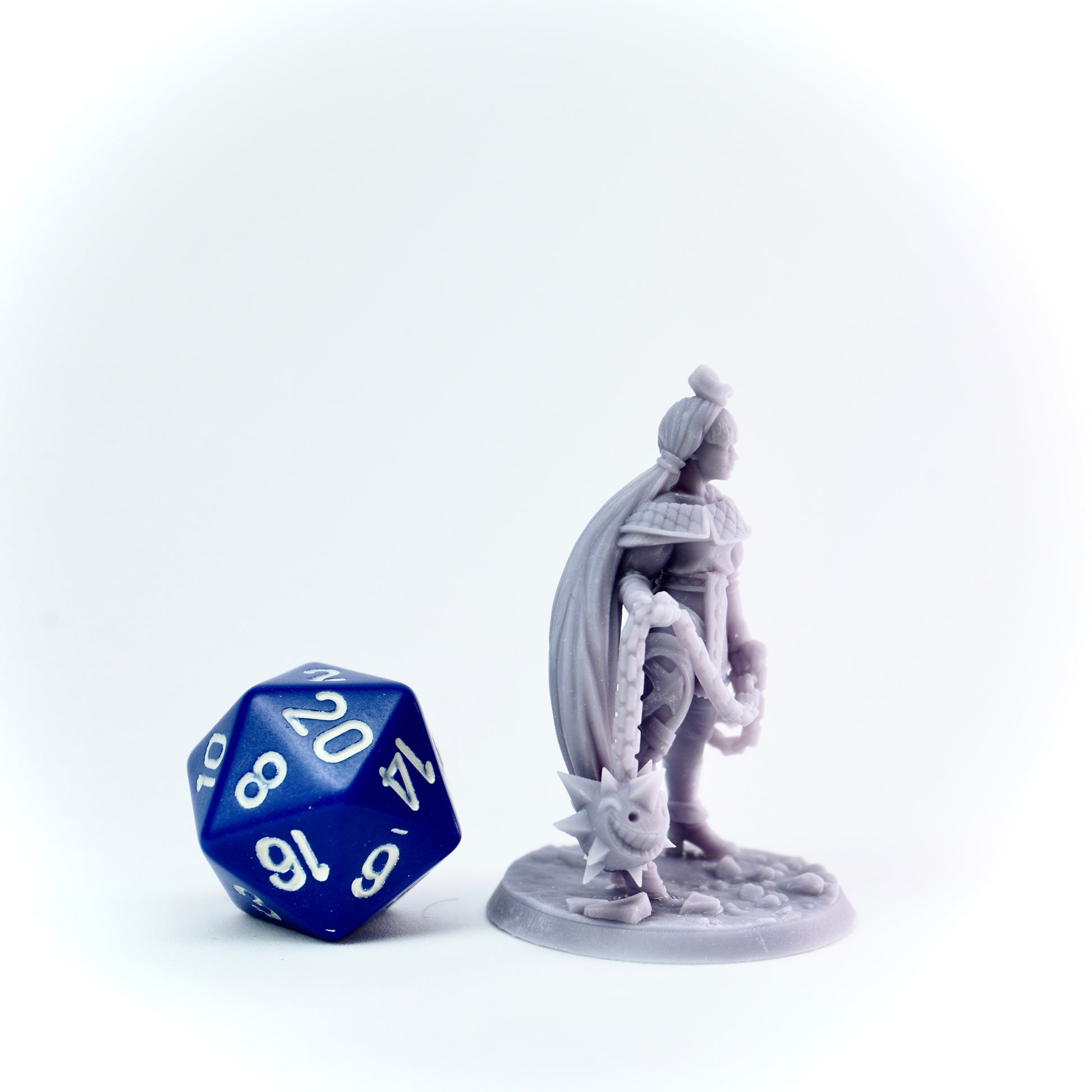 Gray figurine of a warrior with a blue and white die on a white background