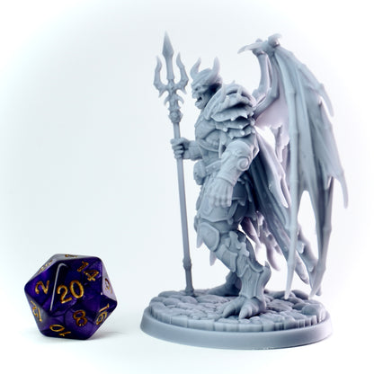 Gray fantasy demon lord figurine with a spear and wings next to a purple polyhedral dice on a white background