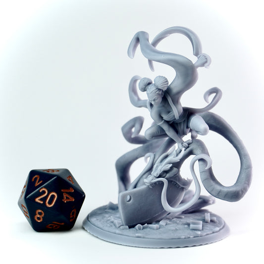 Gray fantasy figurine with dragon spirit and a kitchen knife, next to a black and orange die on a white background