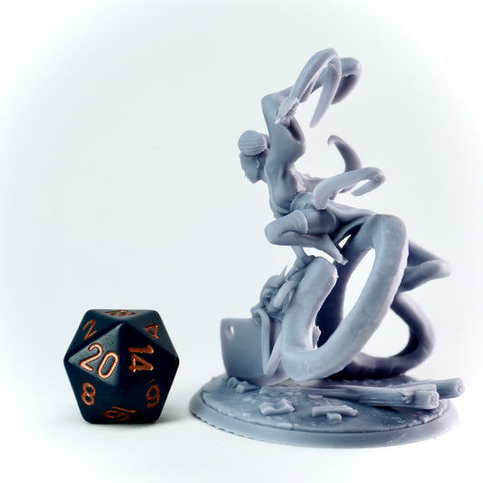 Gray dragon-like figurine with a black polyhedral dice on a white background