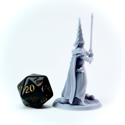Fantasy figurine of a knight with a sword next to a black dice on a white background