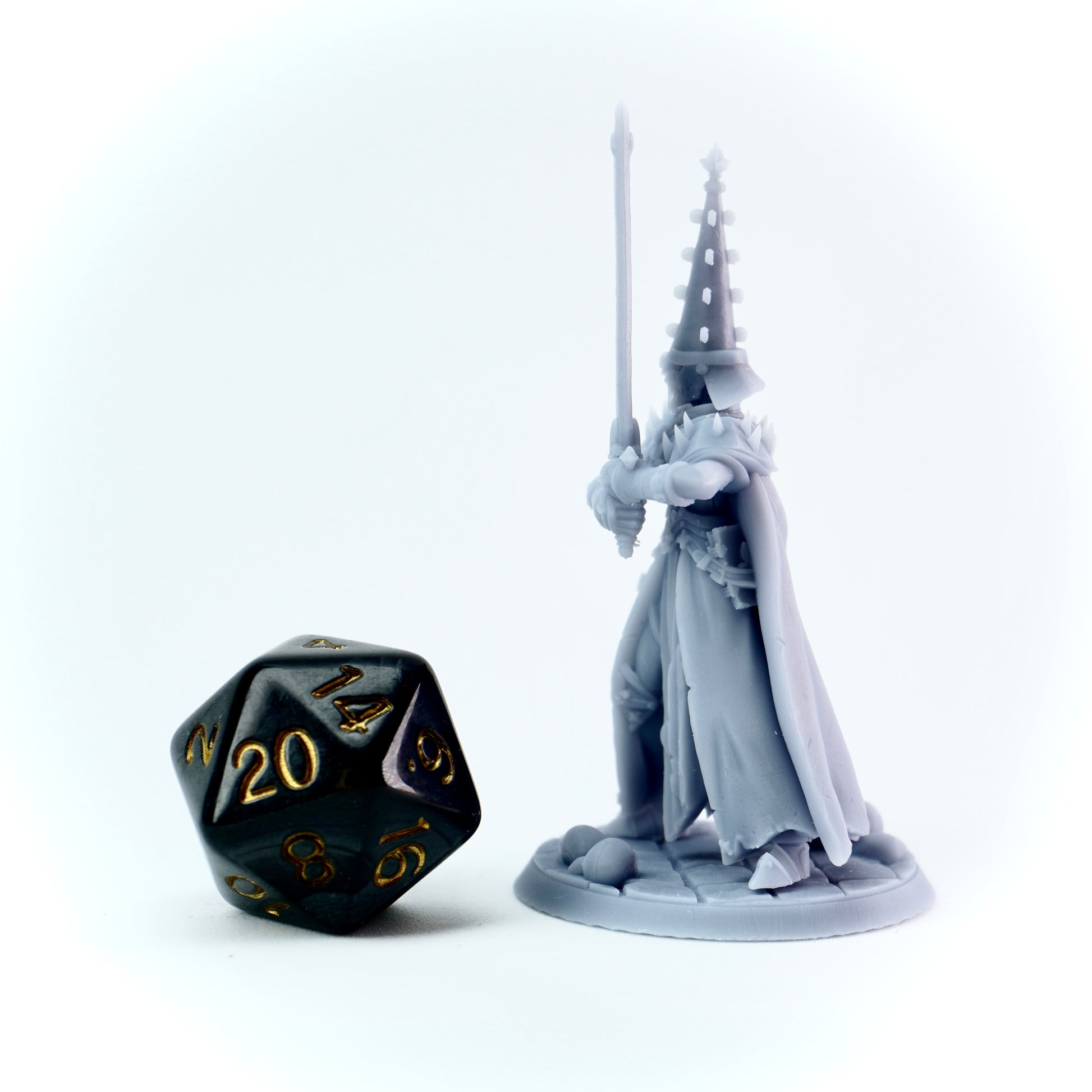 Gray fantasy figure with a sword next to a black polyhedral dice on a white background
