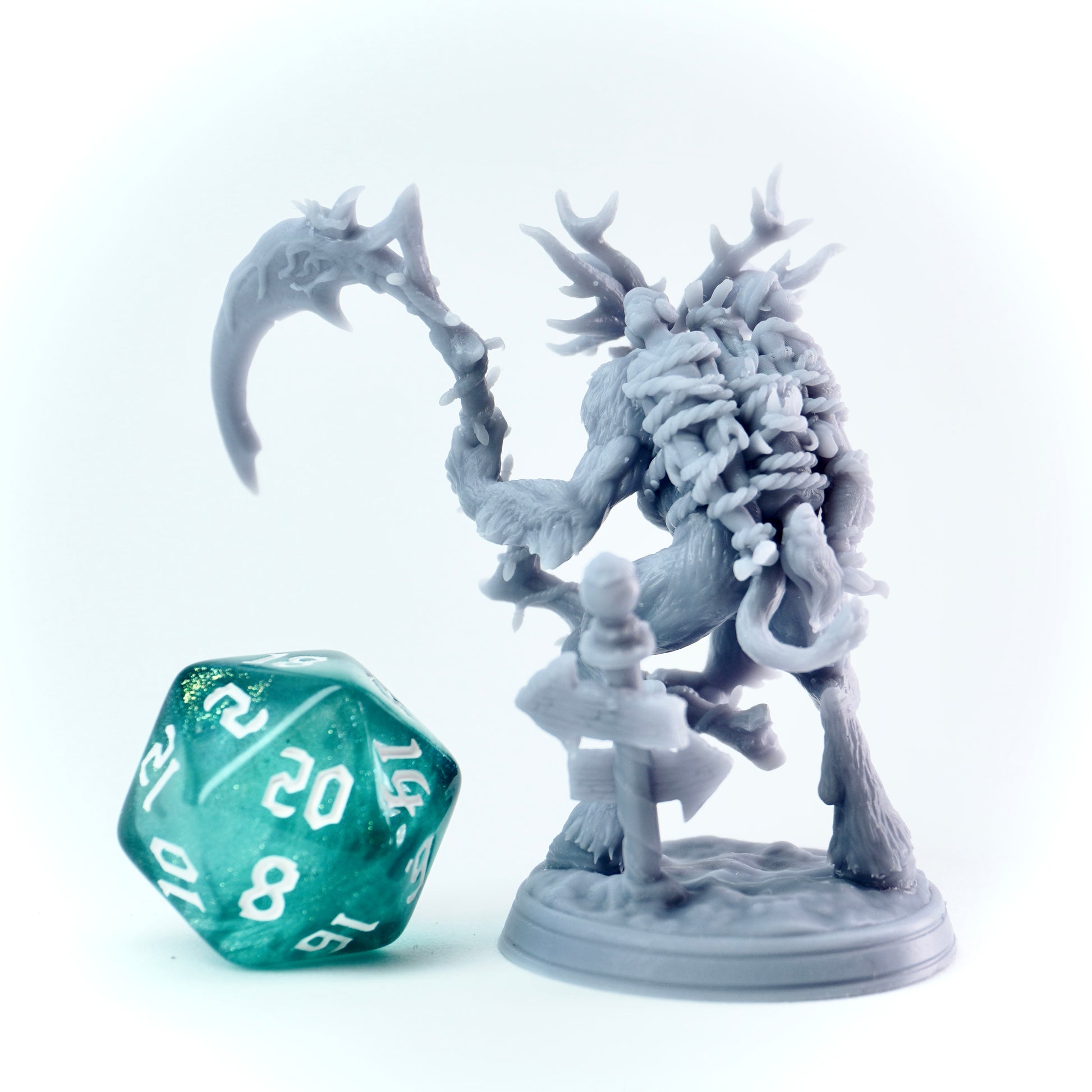 Gray reindeer fantasy figurine with a large weapon next to a green polyhedral dice on a white background