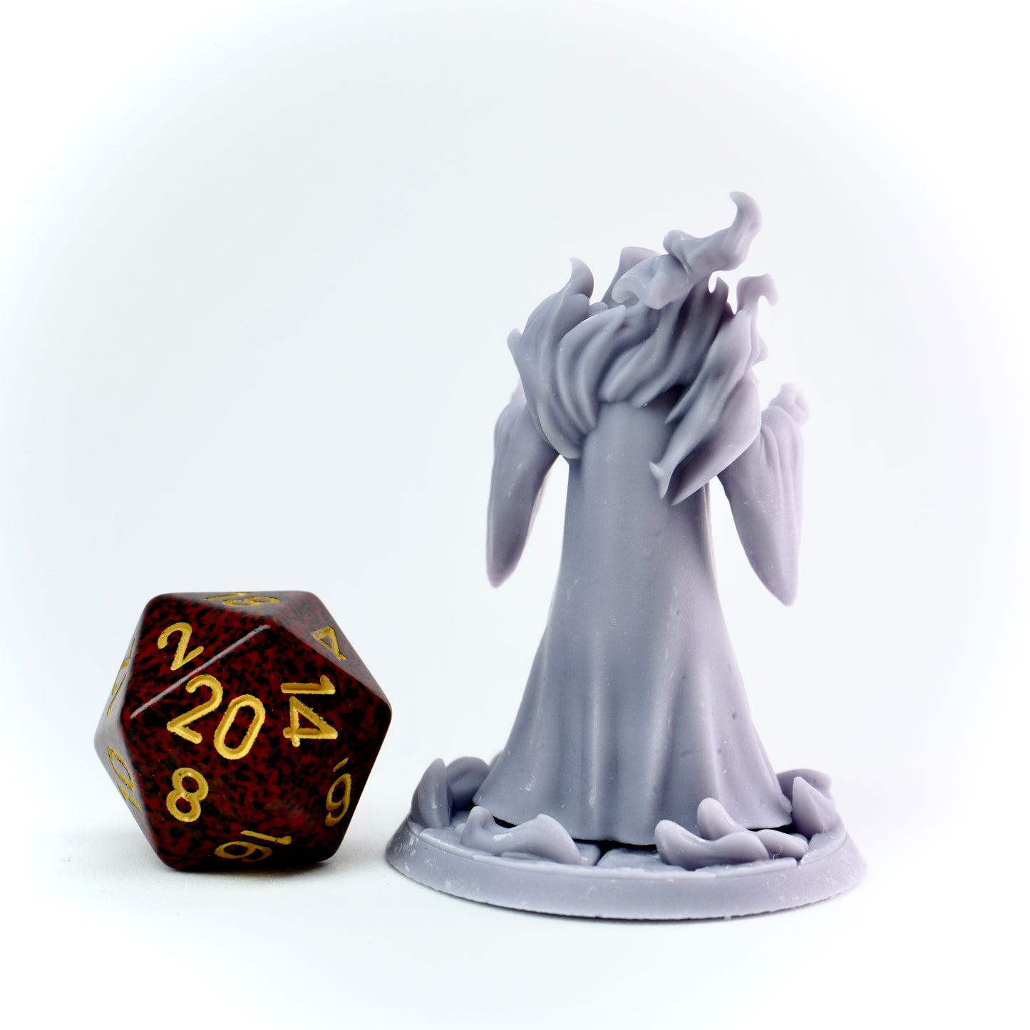 Gray cultist figurine next to a polyhedral dice on a white background