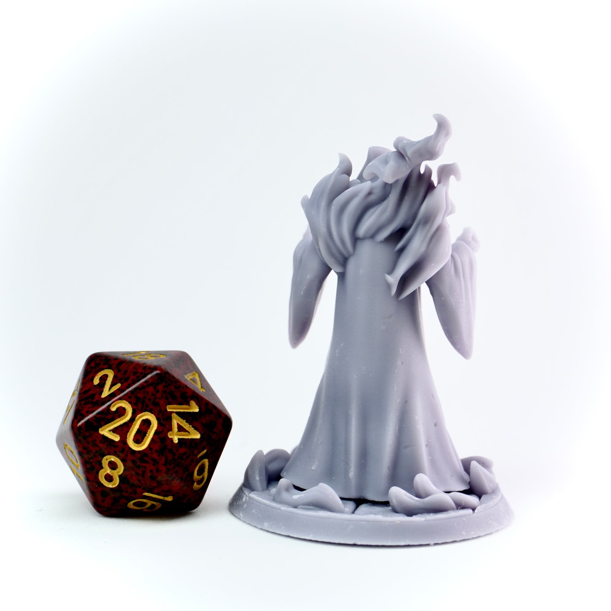 Gray cultist figurine next to a polyhedral dice on a white background
