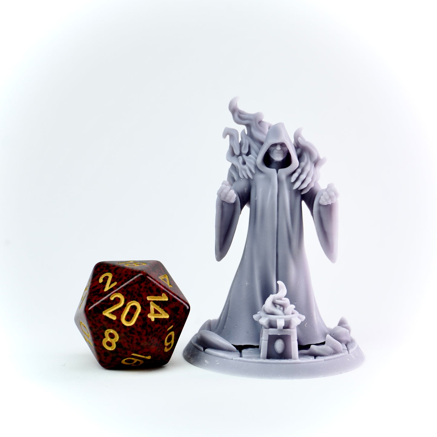 Gray fantasy figurine next to a polyhedral dice on a white background