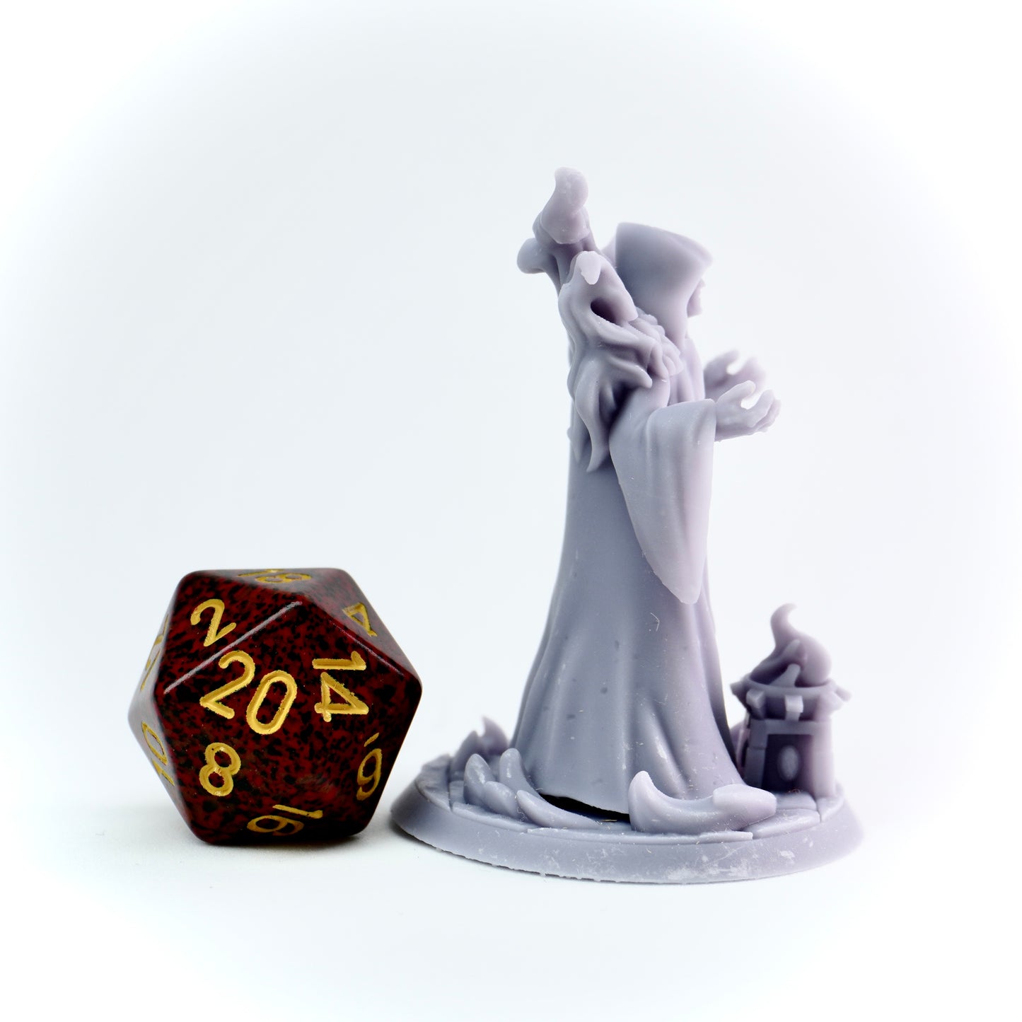 Gray figurine of a cultist with a brown polyhedral dice on a white background