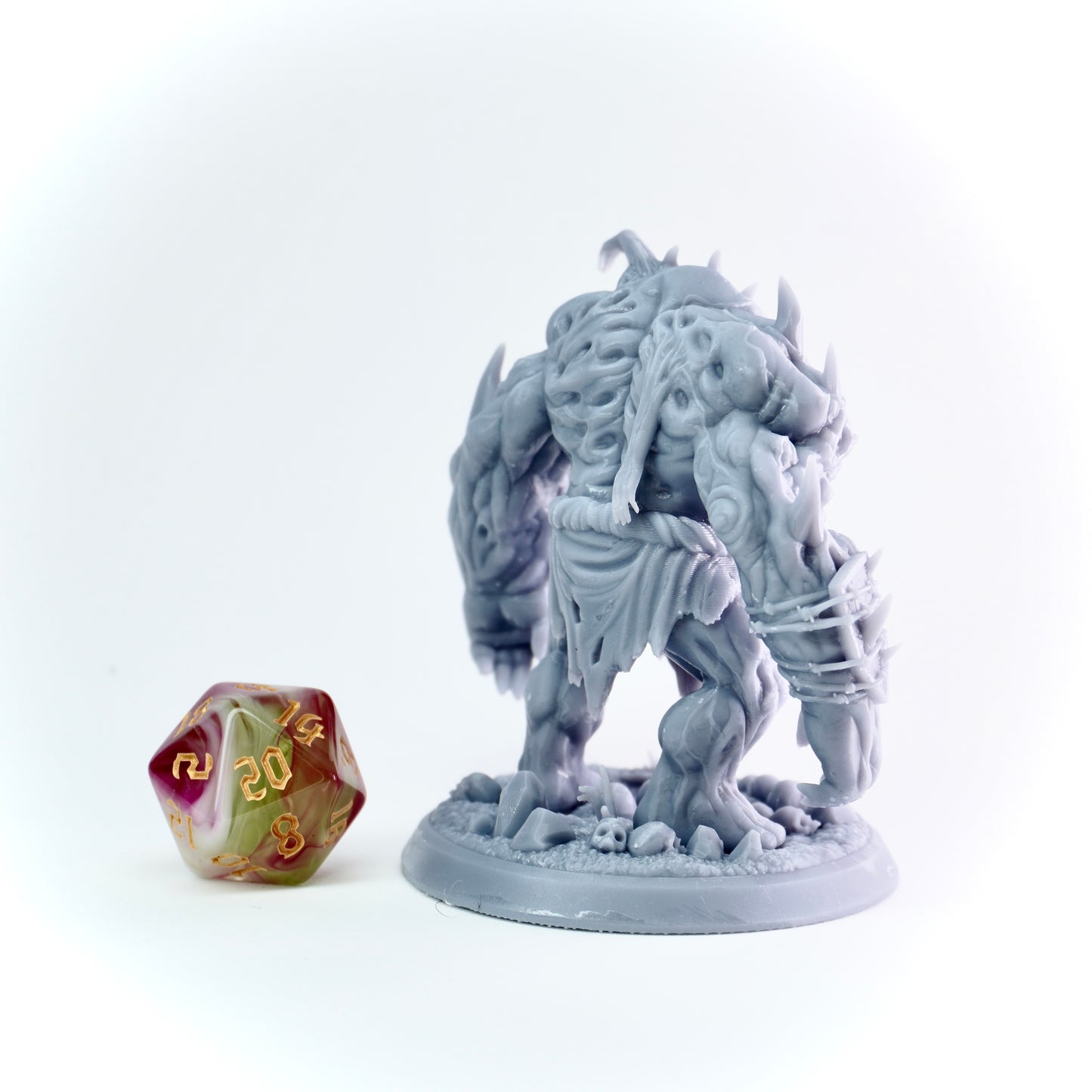 Gray fantasy figurine on a white background with a polyhedral dice.