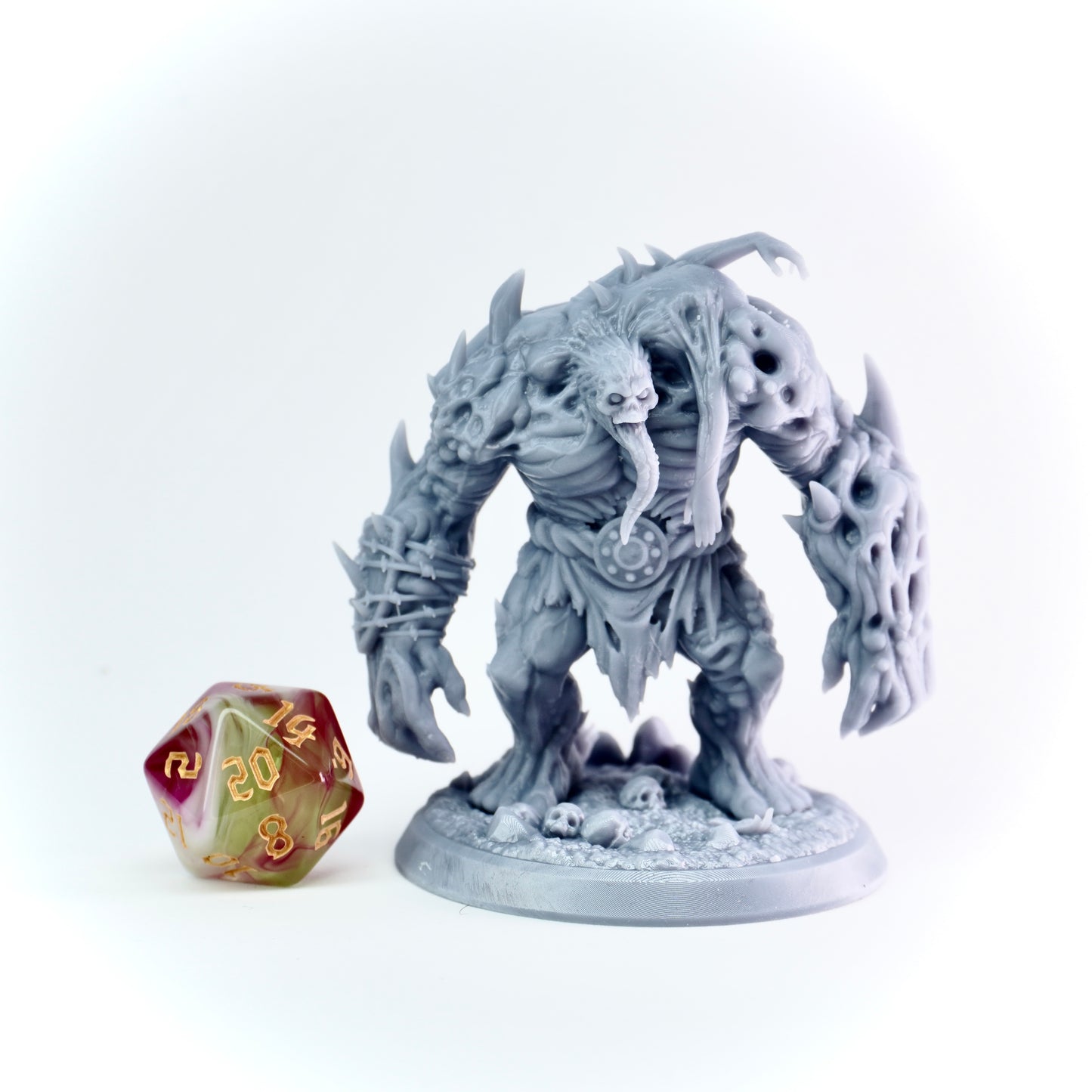 Gray fantasy monster figurine with a D20 dice on a white background