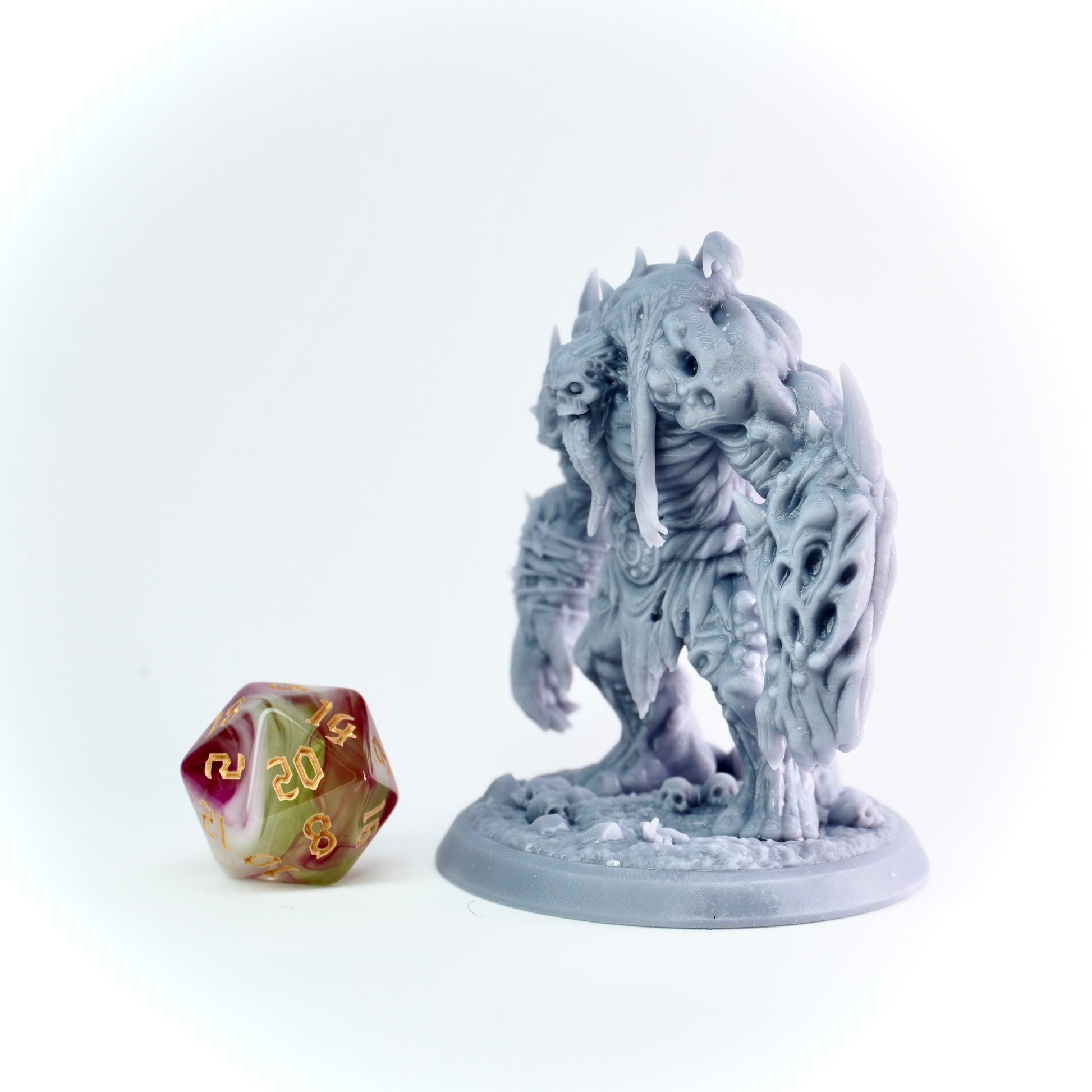 Gray fantasy creature figurine next to a polyhedral dice on a white background