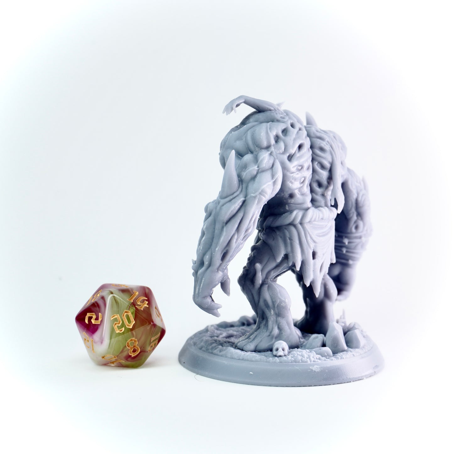 Gray fantasy figurine with a large axe next to a polyhedral dice on a white background