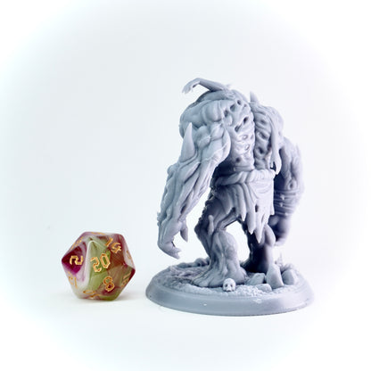 Gray fantasy figurine with a large axe next to a polyhedral dice on a white background