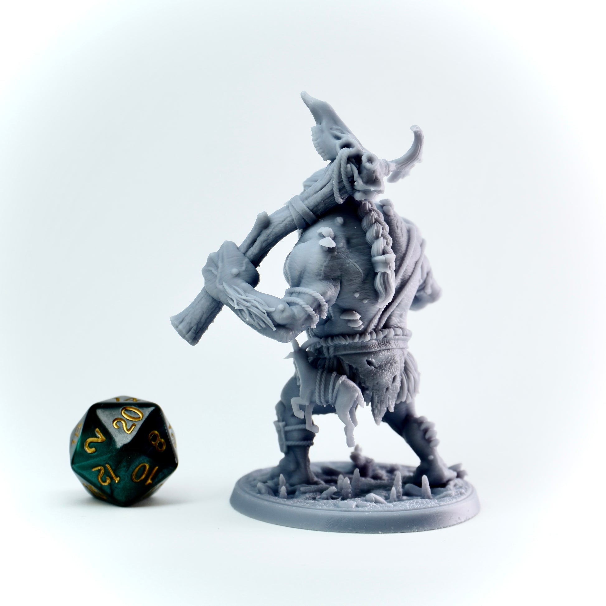 Gray fantasy troll figurine with a weapon next to a green polyhedral dice on a white background