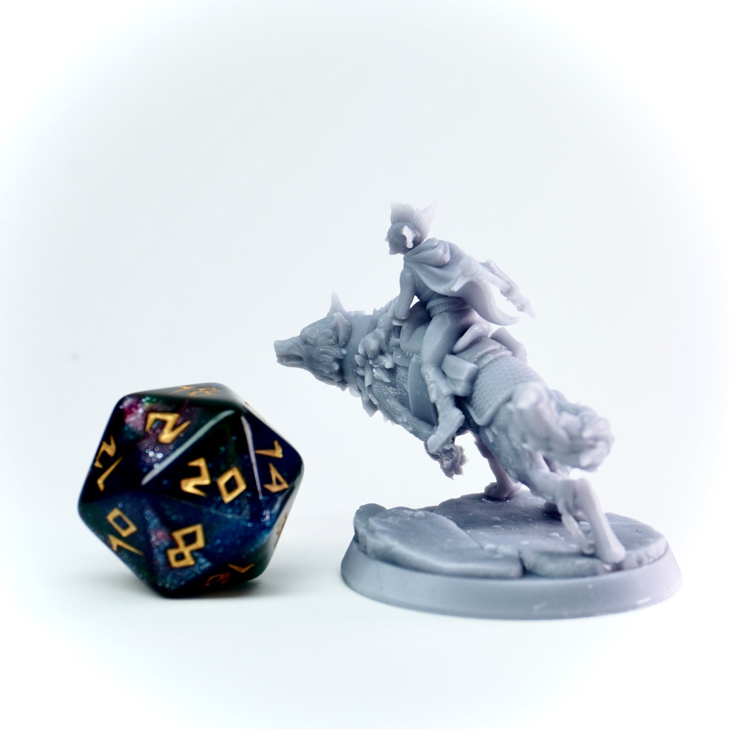 Gray figurine of a person on a wolf with a large polyhedral dice next to it on a white background