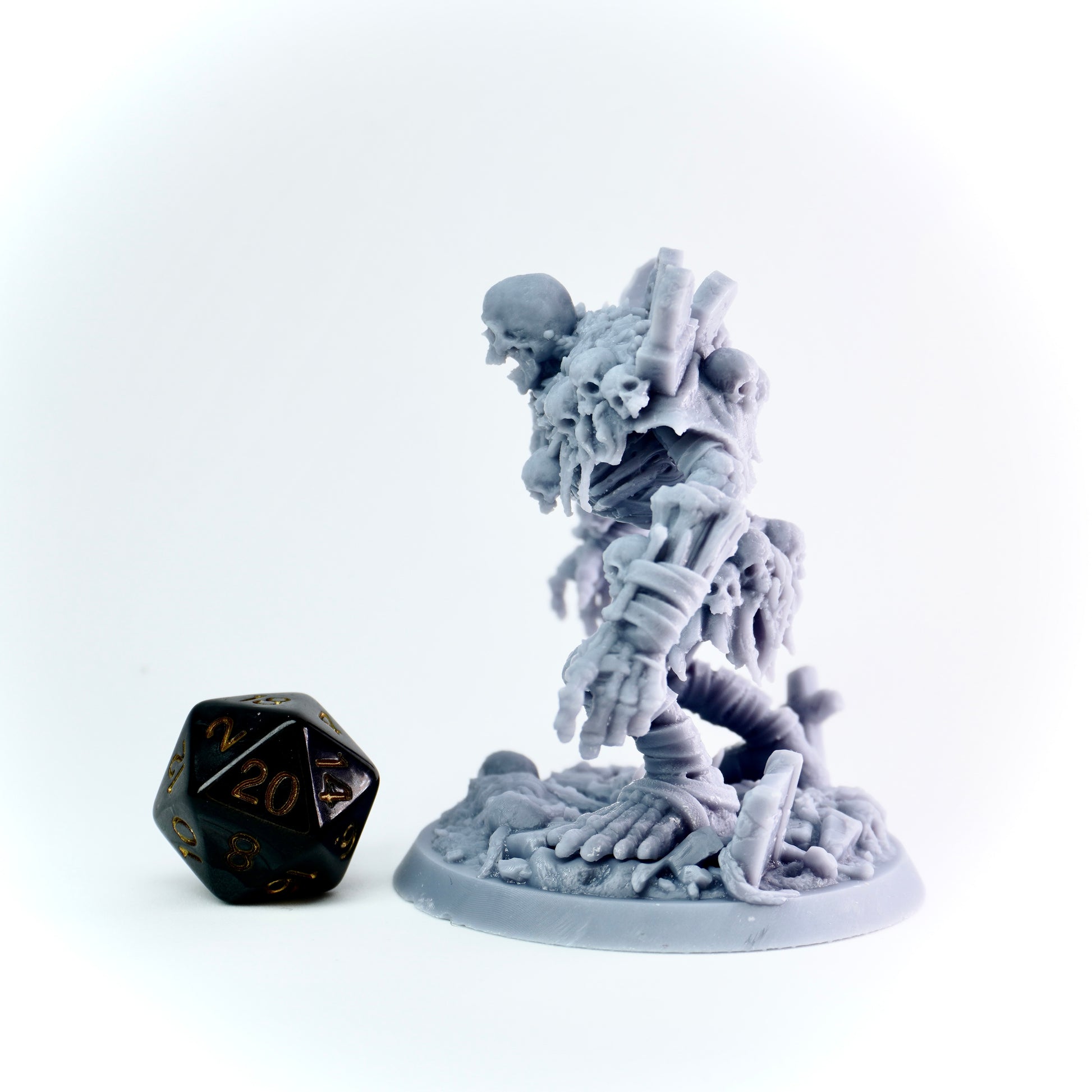 Gray miniature figurine of a skeleton with a black polyhedral dice on a white background