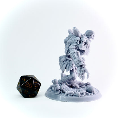 Gray miniature figurine with intricate details on a white background, next to a black and gold die.