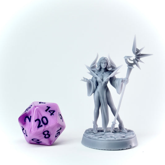 Gray fantasy figurine with a staff next to a purple polyhedral dice on a white background