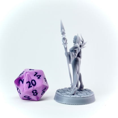 Gray fantasy figurine with a purple polyhedral dice on a white background
