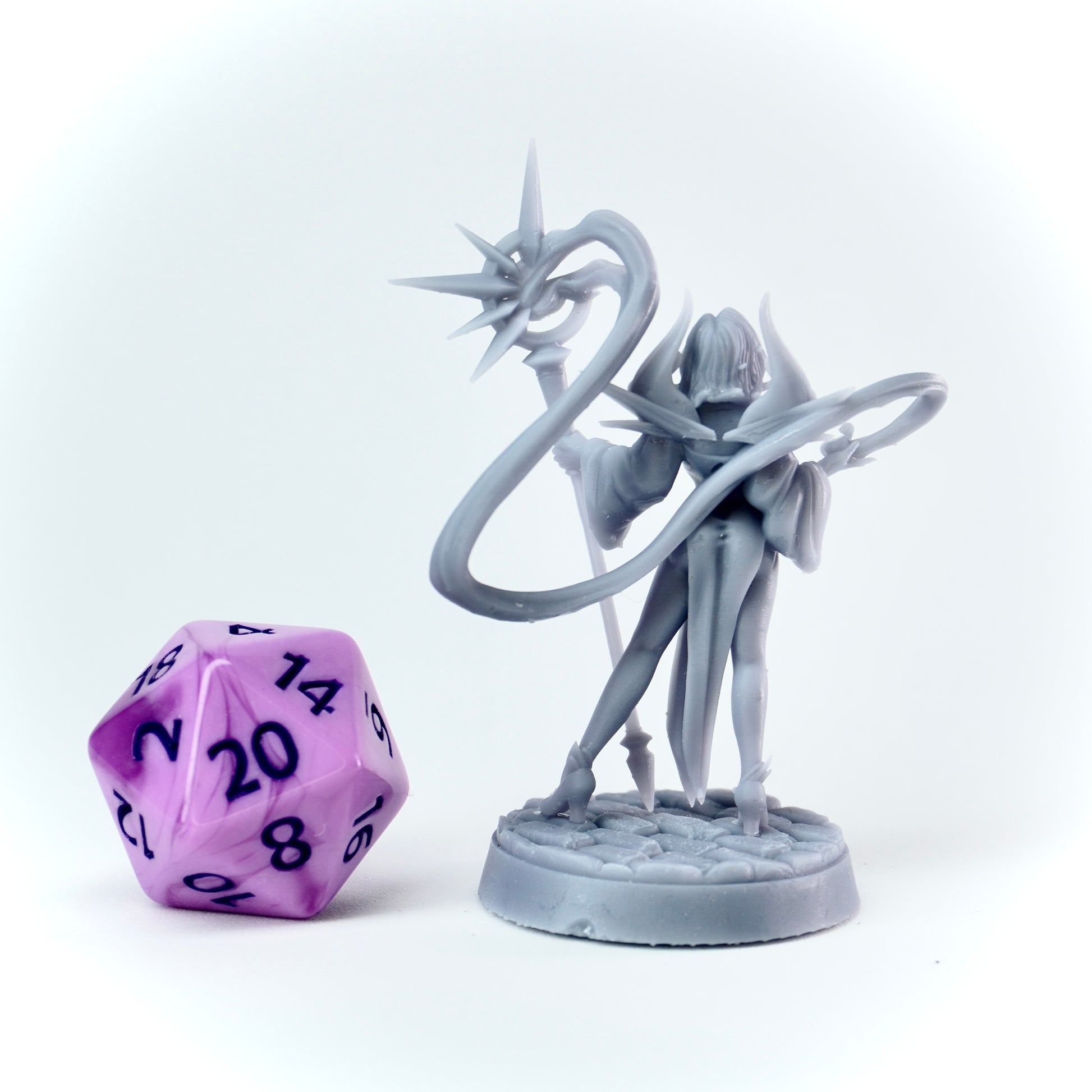 Gray fantasy figurine with a purple polyhedral dice on a white background