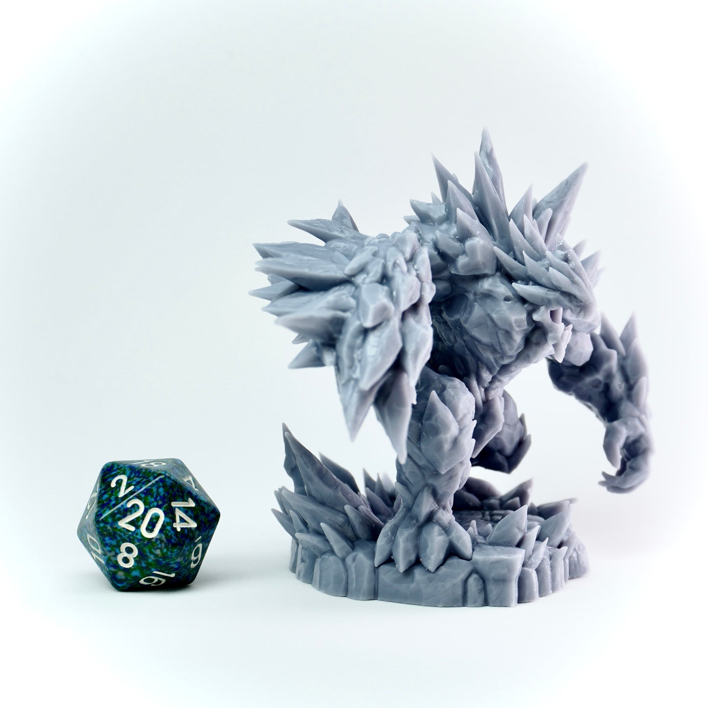 Gray dragon-like figurine on a white background with a D20 dice.