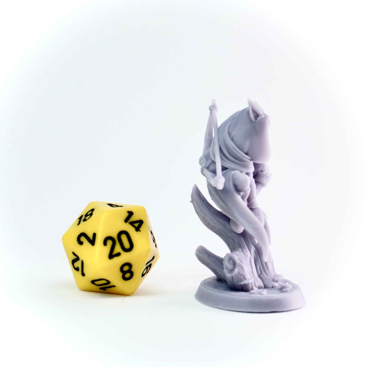 Yellow polyhedral dice next to a gray fantasy figurine on a white background